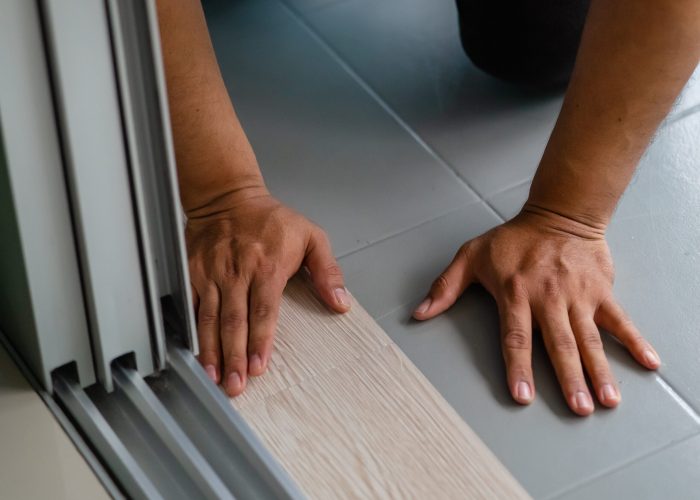 A person installing new vinyl tile floor, a DIY home project. A person installing new vinyl tile floor, a DIY home project.